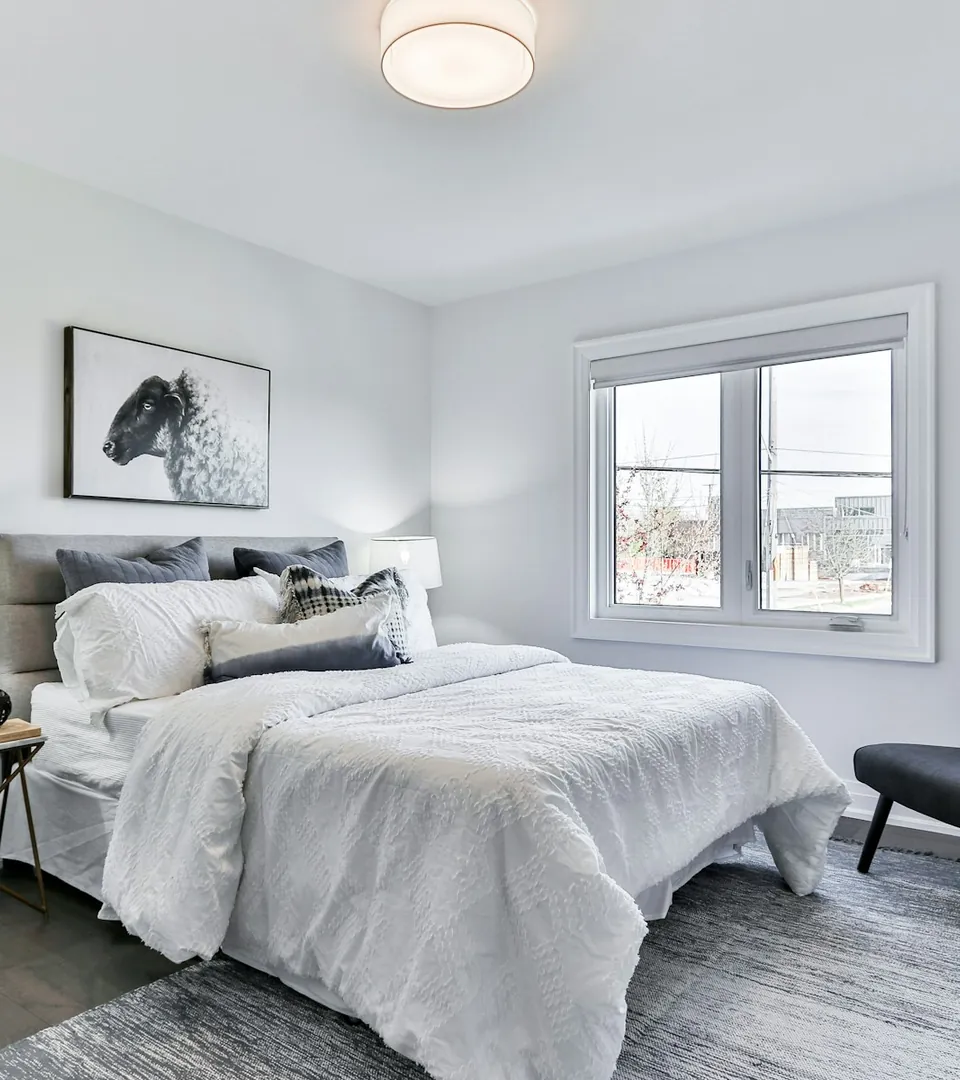 A calm bedroom with neutral bedding and natural light
